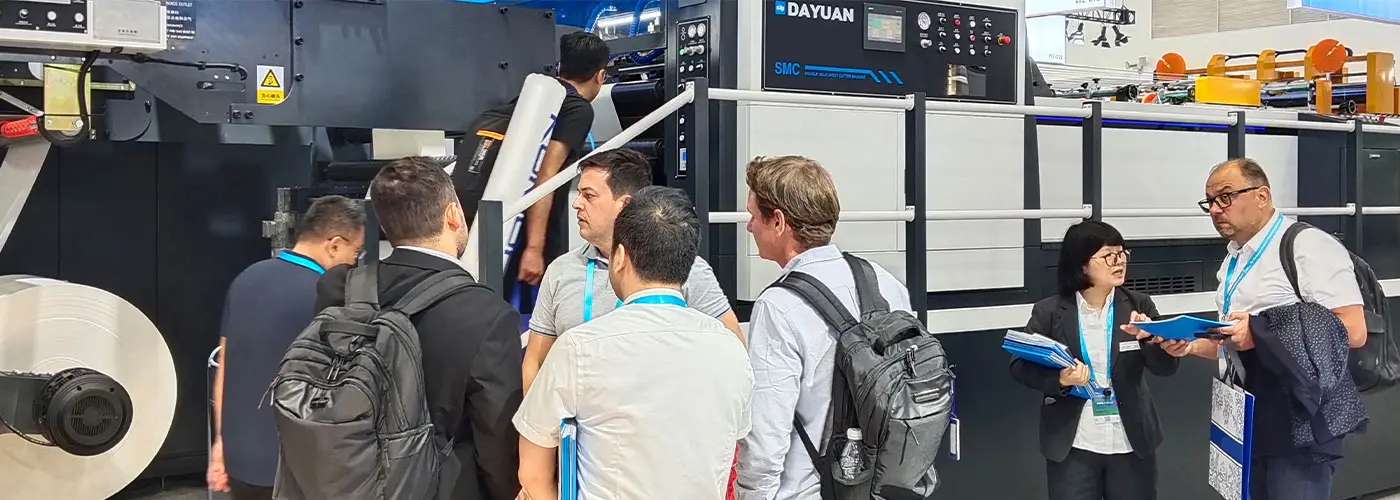 Dayuan staff introducing SMC die-cutting machine to international visitors at an exhibition